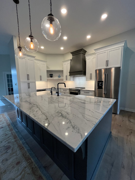 Remodeled kitchen with a marble waterfall island and pendant lighting