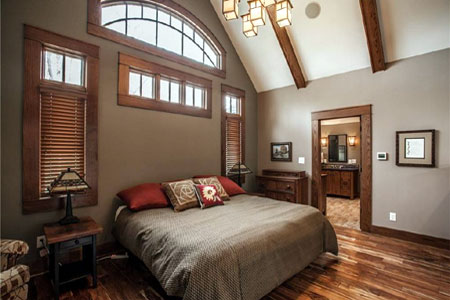 Finished bedroom with vaulted ceiling, wood trim and arched window
